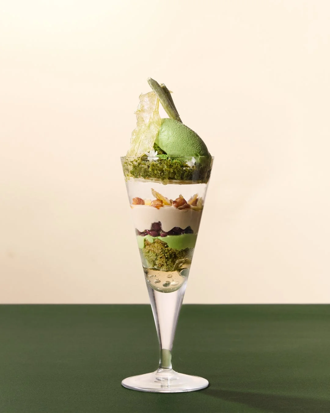 透明なグラスに盛り付けられた抹茶アイスクリームと様々な層が美しいパフェ