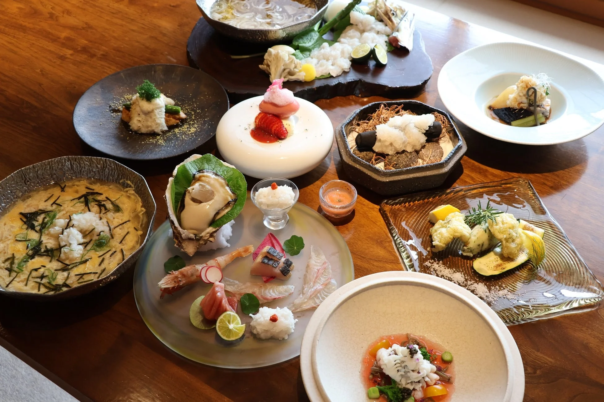 木製のテーブルに並べられた豪華な日本料理の数々。刺身、鍋物、揚げ物、デザートなど、彩り豊かで芸術的な会席料理が贅沢な食卓を演出しています。