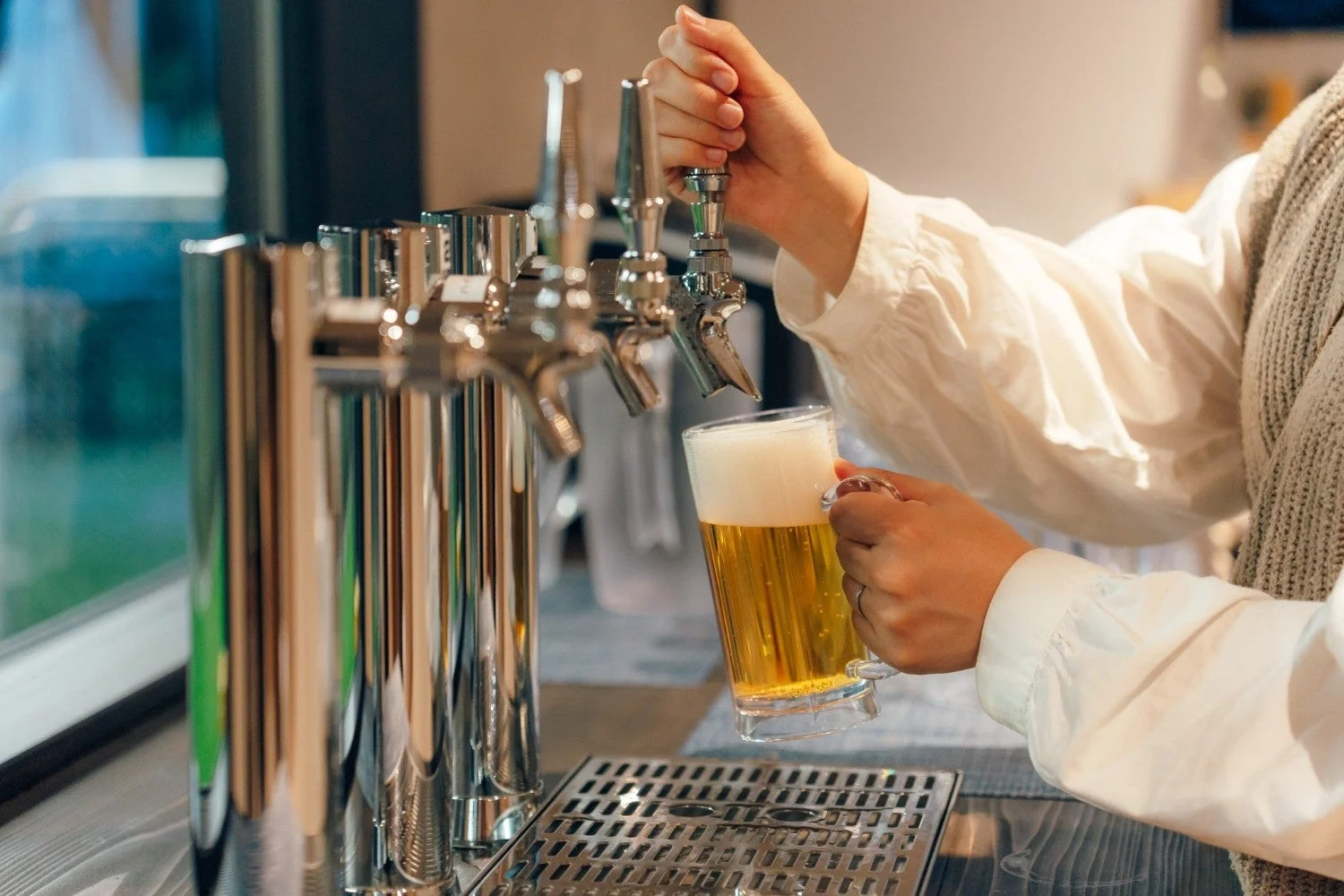ビアサーバーからグラスにビールが注がれている様子を捉えた画像です。黄金色のビールに白い泡が立ち、冷たそうな雰囲気が伝わってきます。