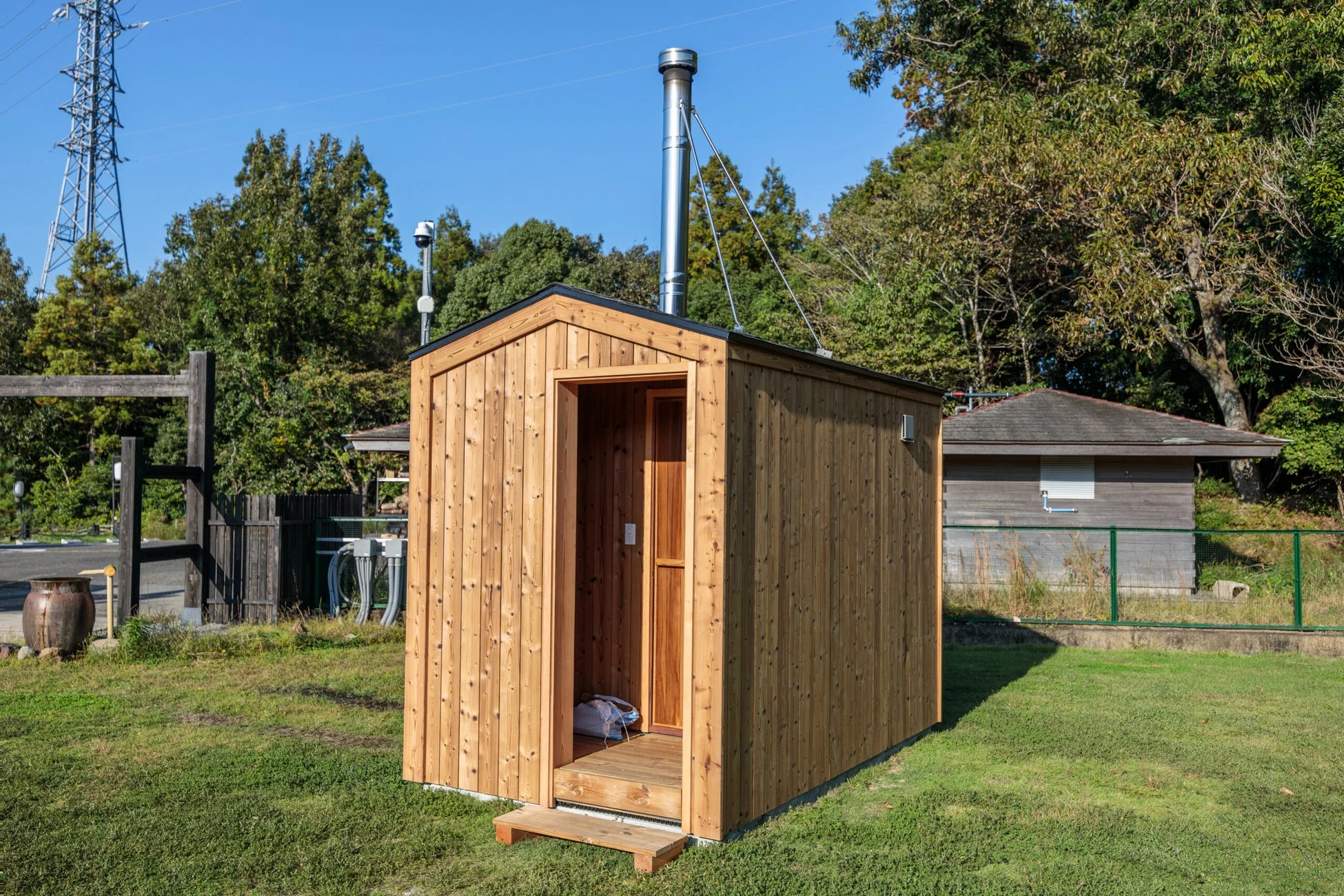青空の下、芝生の上に立つシンプルな木製の小屋が写っています。